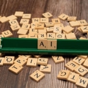 Wooden Scrabble tiles spell out "AI" on a tile rack surrounded by scattered letters. Can AI blogging fully replace the expertise of a human writer? SEO services for therapists combine both, pairing efficiency with genuine clinical insight.