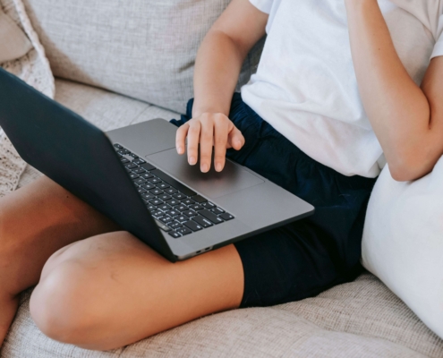 Person sitting on a couch with a laptop, symbolizing the ongoing work of growing a therapy practice through SEO for therapists.