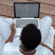 Overhead view of a person reading text on a laptop while sitting cross-legged, representing the importance of AI accuracy and carefully reviewing content to catch AI misinformation before publishing.
