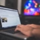 A hand types on a laptop displaying a WordPress blog post editor with a colorful light display visible on a monitor in the background. Publishing consistent thoughtful content on your therapy website is one of the most powerful ways to build the kind of authority Google and your ideal clients both look for.